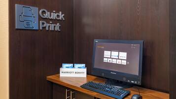 A hotel reception desk with a "Quick Print" sign, a Lenovo computer, a keyboard, a mouse, and a sign for "Marriott Bonvoy."