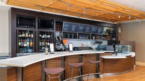 A modern bar area with a curved counter, multiple seating options, and a variety of liquor bottles and glasses.