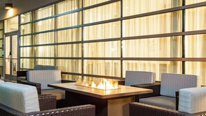 A cozy outdoor seating area with wicker furniture and a central fire feature.