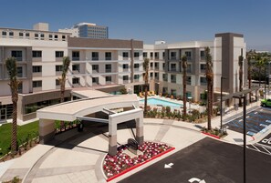 A modern hotel with a pool, palm trees, and a parking area. - Courtyard by Marriott Santa Ana Orange County (Santa Ana)