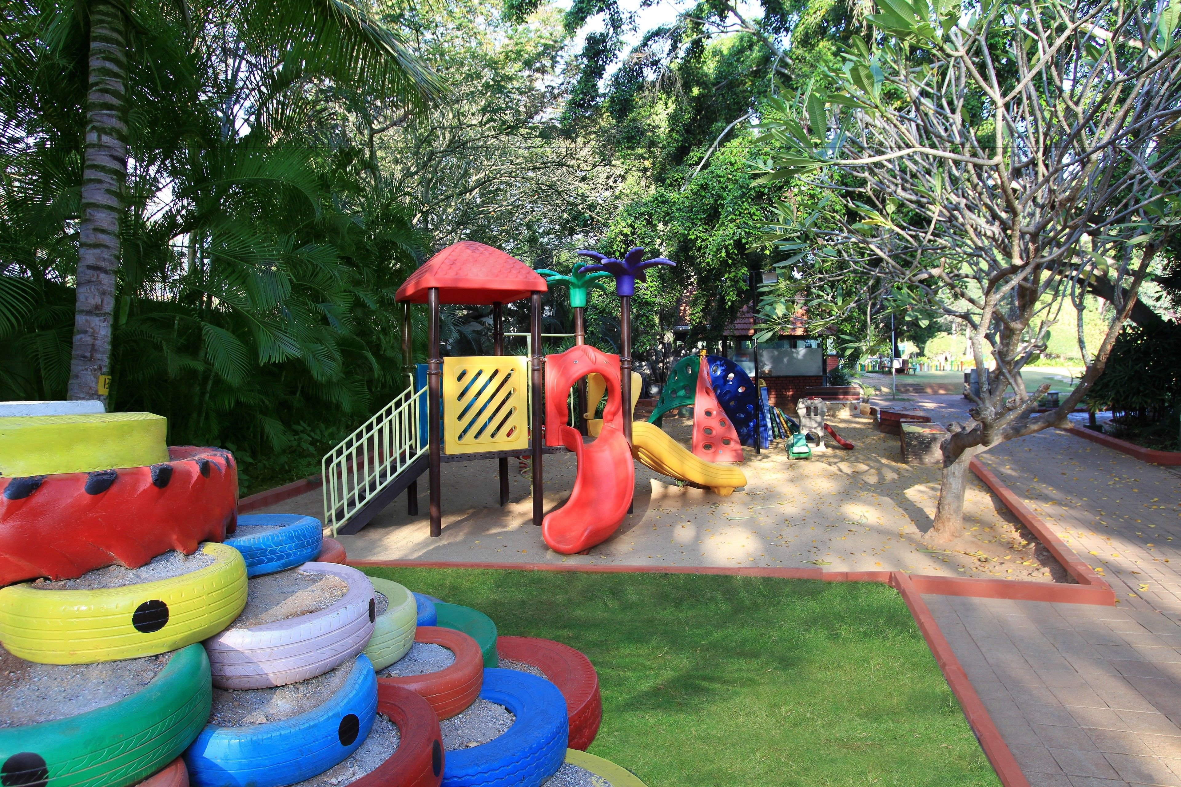 A playground with tire play structures, a slide, and a climbing area.