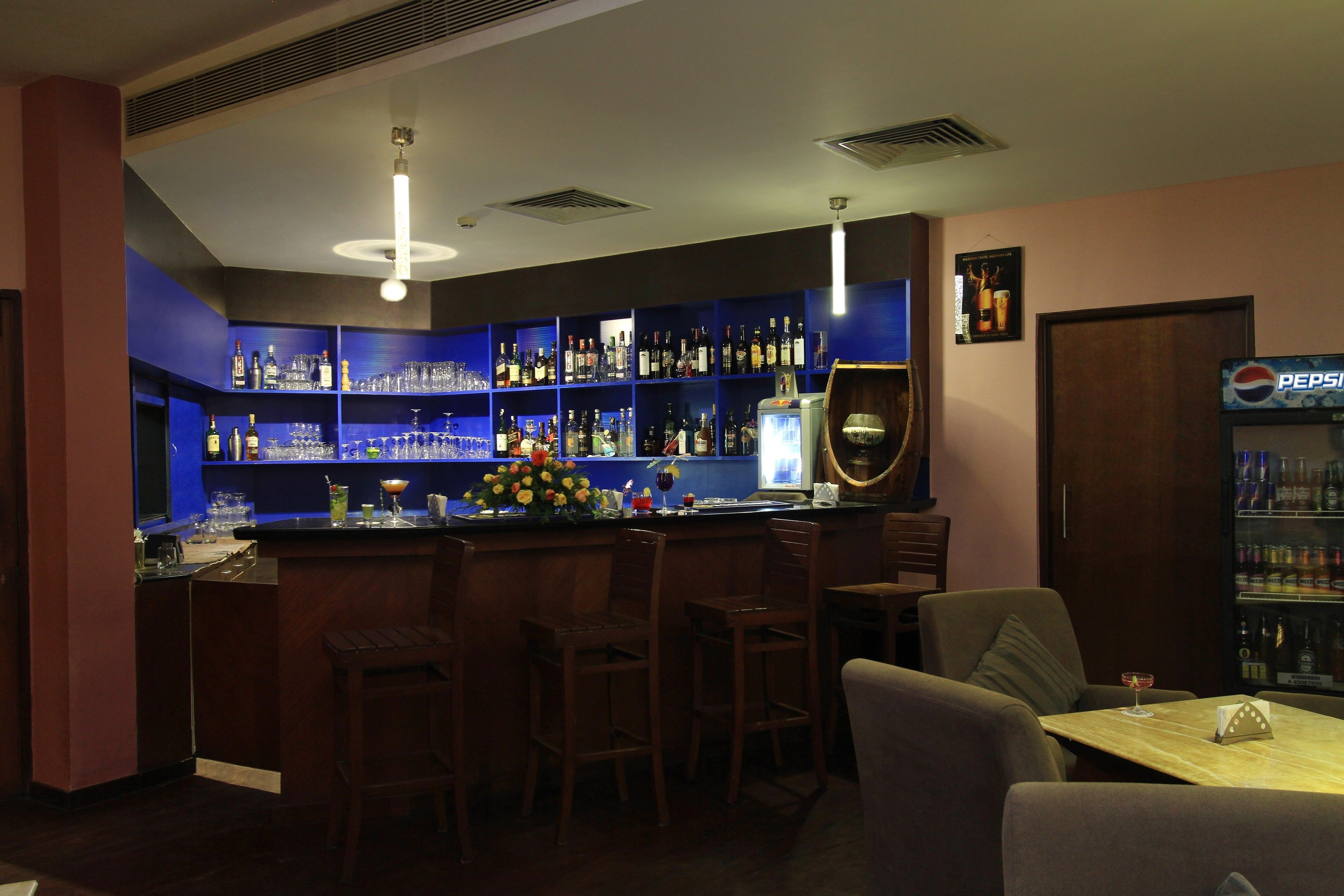 A bar area with a counter, multiple shelves of bottles, and seating.