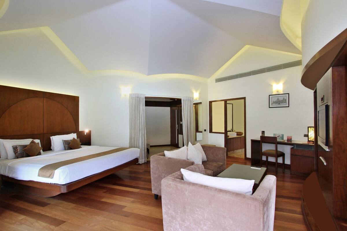 Una habitación de hotel con una cama grande, dos sofás, un escritorio y un espejo.