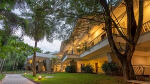 Un hotel de varios pisos con un césped cuidado, mobiliario exterior y una escalera que conduce a los pisos superiores.