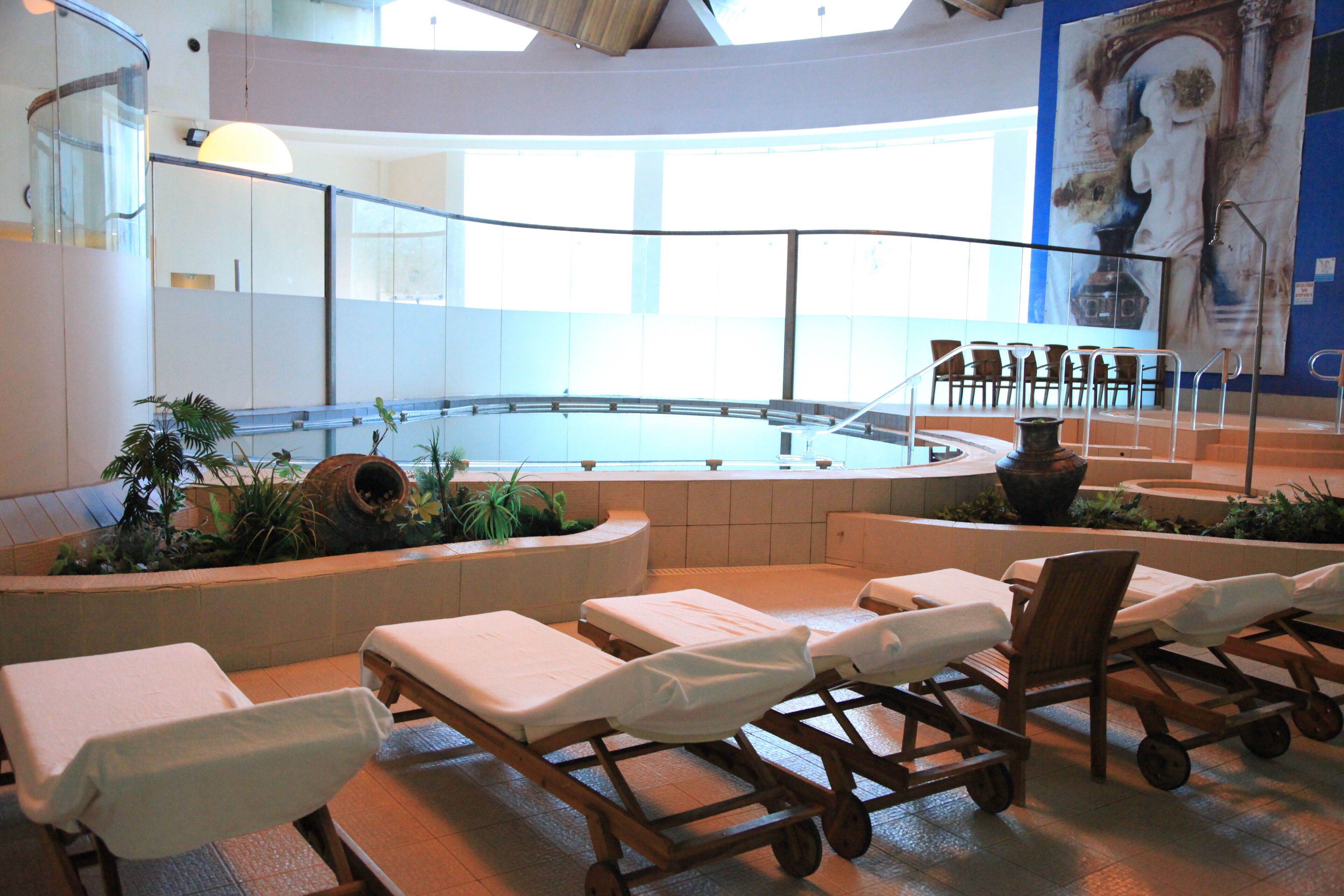A spa area with massage tables, a pool, and a large mural on the wall.