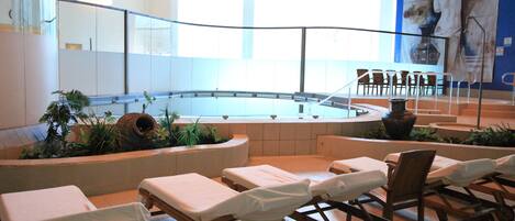 A spa area with massage tables, a pool, and a large mural on the wall.