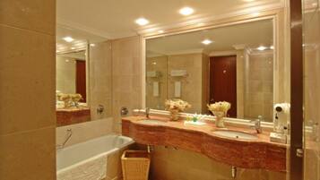 Un baño con un espejo grande, dos lavamanos, una bañera y una cesta de mimbre.
