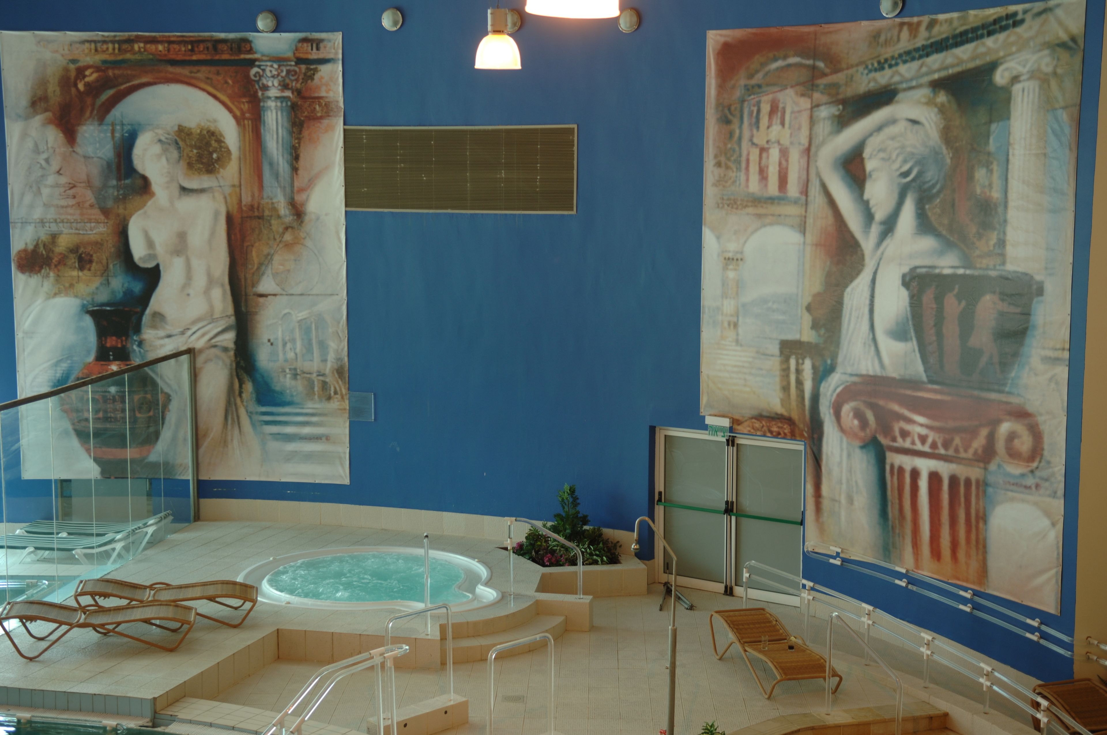 A spa area with a hot tub, seating, and classical art murals on the walls.