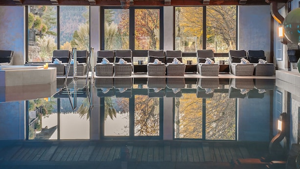 A modern indoor pool with a clear view of autumn trees through large windows. - Alpin & Wellness Resort Hotel Ludwig Royal  (Oberstaufen)