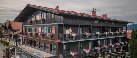 A hotel with a balcony, outdoor seating, and flower arrangements.