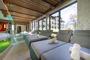 Una piscina techada, una piscina al aire libre, sombrillas