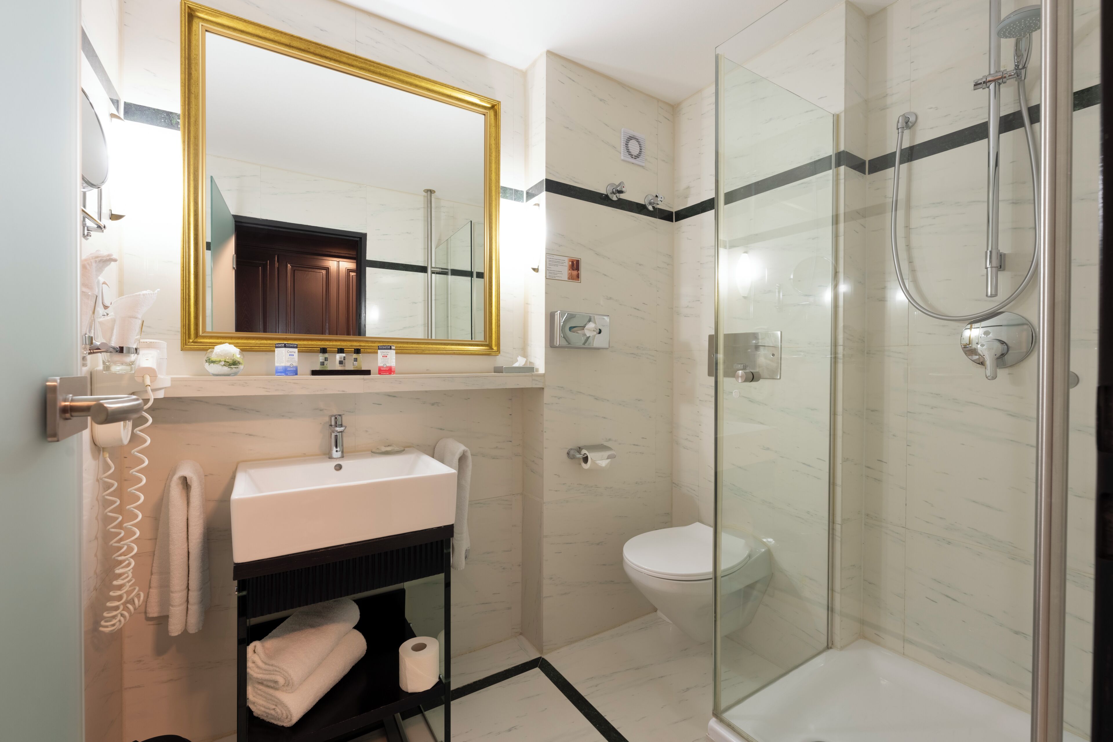 A bathroom with a sink, mirror, toilet, and glass-enclosed shower.