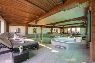 Una piscina techada, una piscina al aire libre, sombrillas