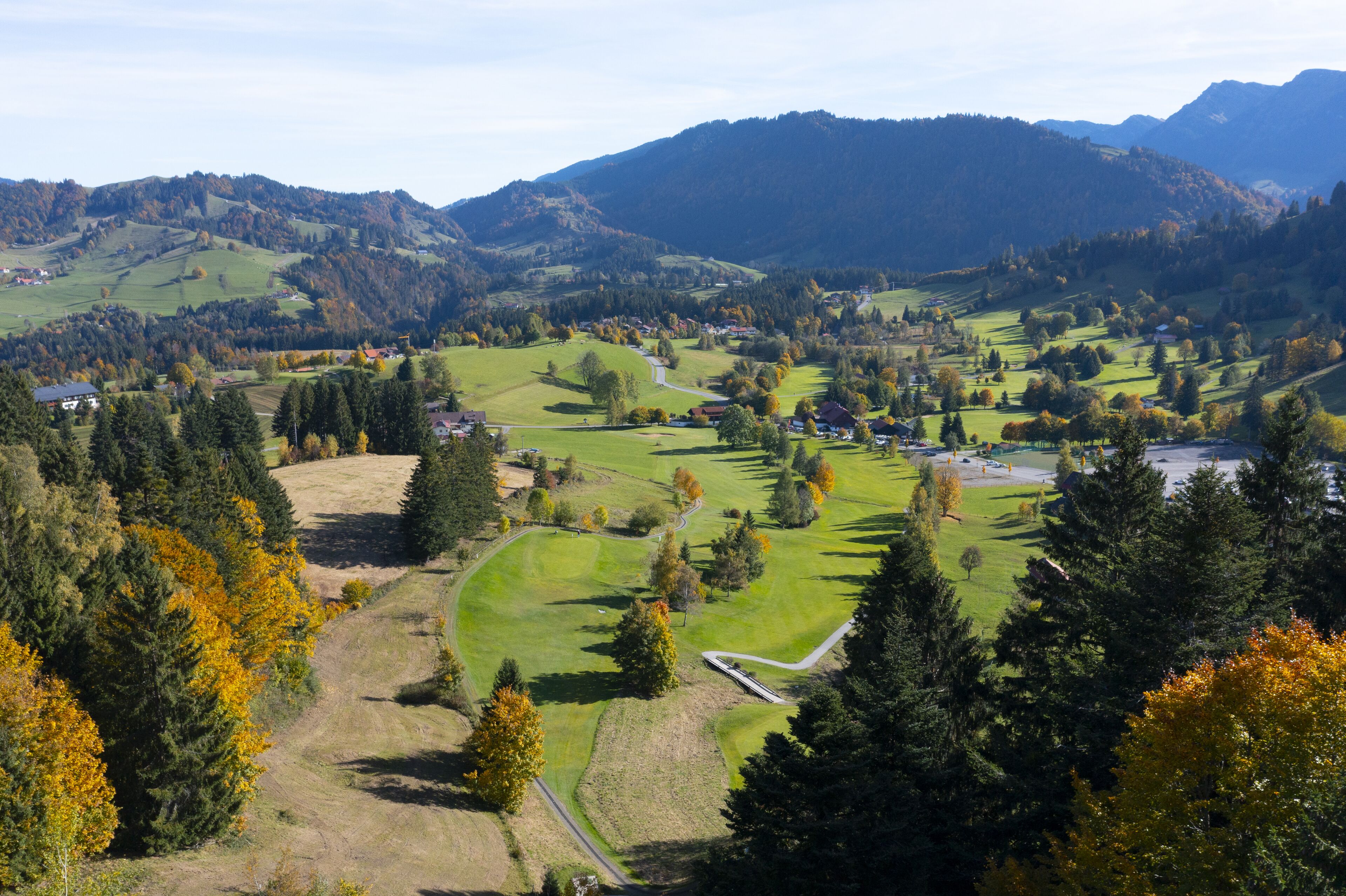 Vista panorámica de un paisaje rural con colinas onduladas, un camino sinuoso y casas dispersas.