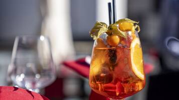 Ein Tisch, gedeckt mit einer roten Tischdecke, ein Cocktail mit Fruchtbeilage und Besteck.