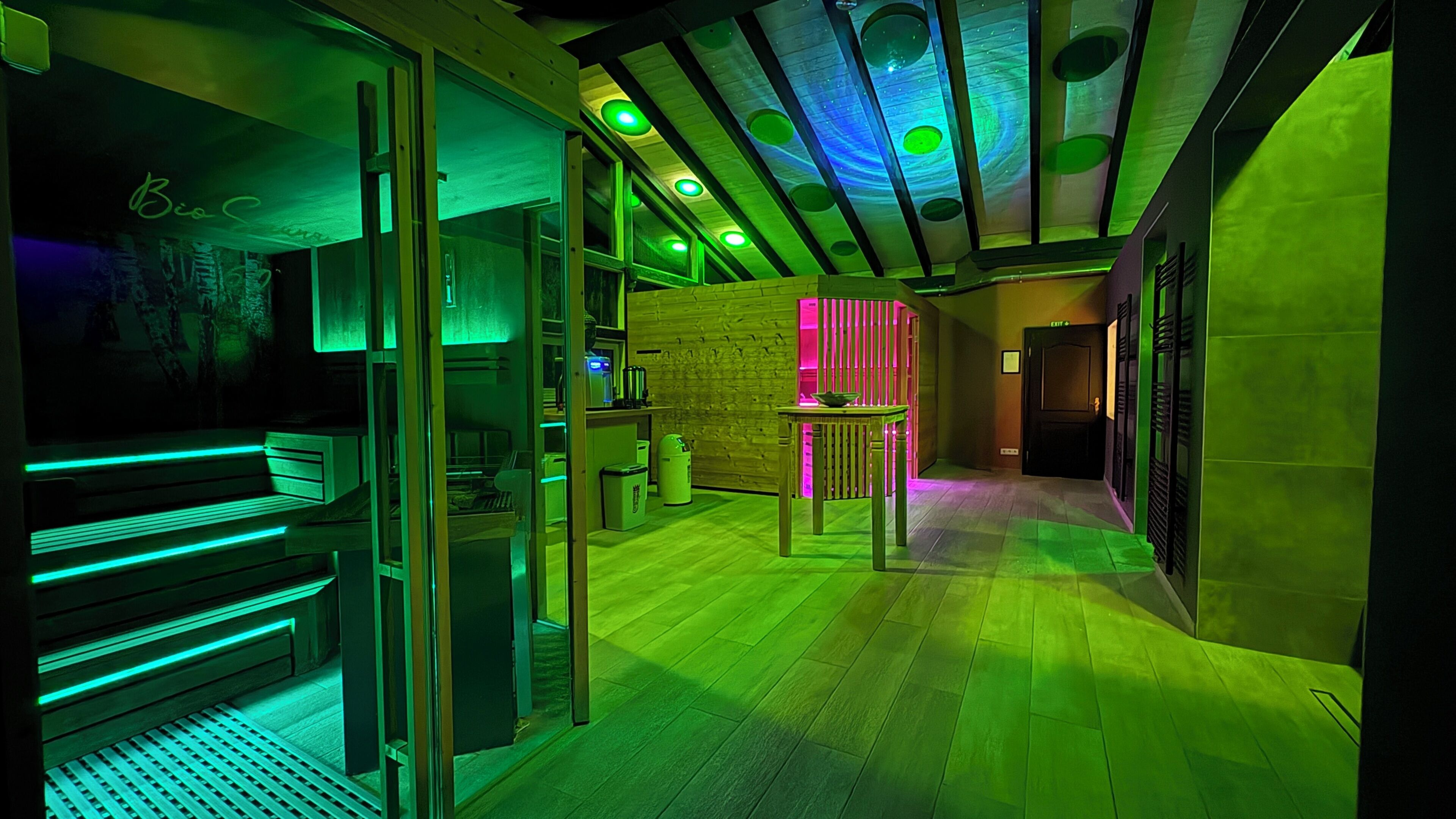 A modern interior with a wooden floor, glass partitions, and a neon-lit ceiling.