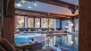 A luxurious spa area with a hot tub, reclining chairs, and a glass-enclosed pool. - Alpin & Wellness Resort Hotel Ludwig Royal  (Oberstaufen)