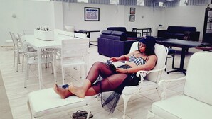 A person seated on a white chair in a room with white furniture, including a table and chairs. - Tariman INN (Umhlanga)