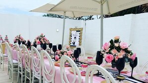 A long table set with pink tablecloths, white chairs, and floral centerpieces. - Tariman INN (Umhlanga)