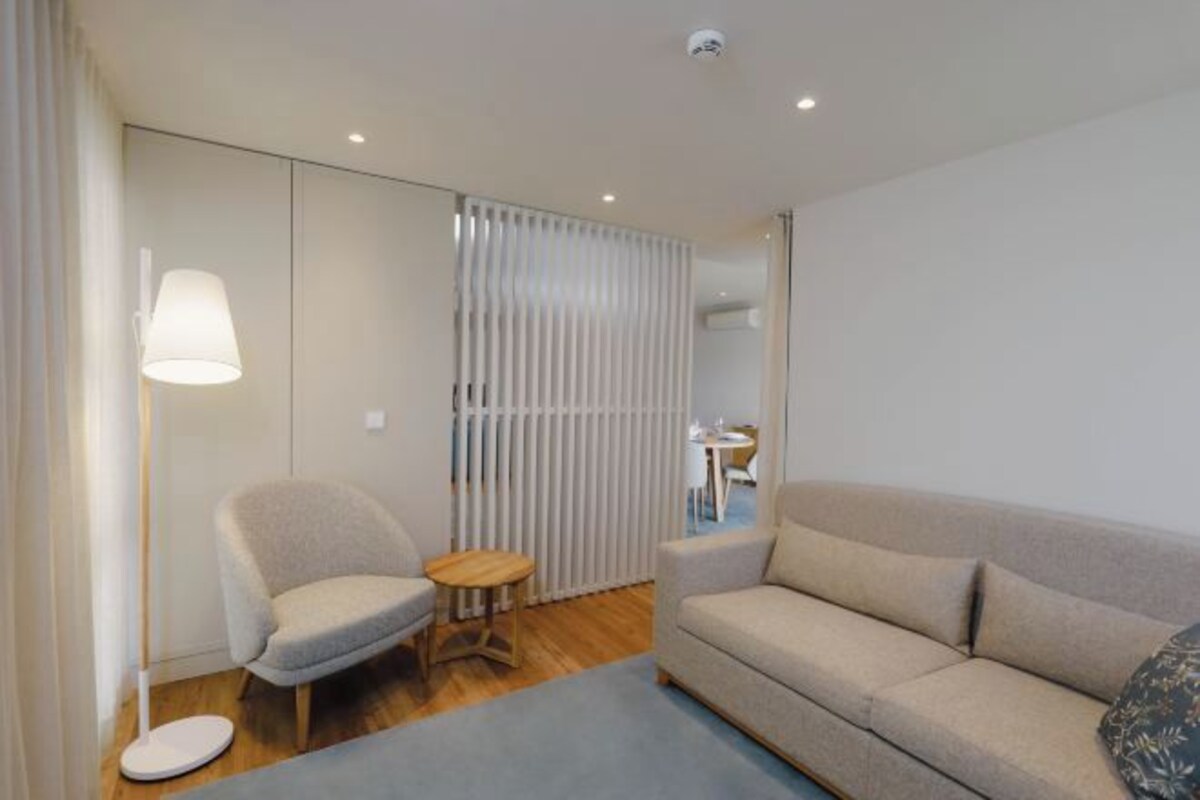 Una sala moderna con sofá, sillón y una mesita.