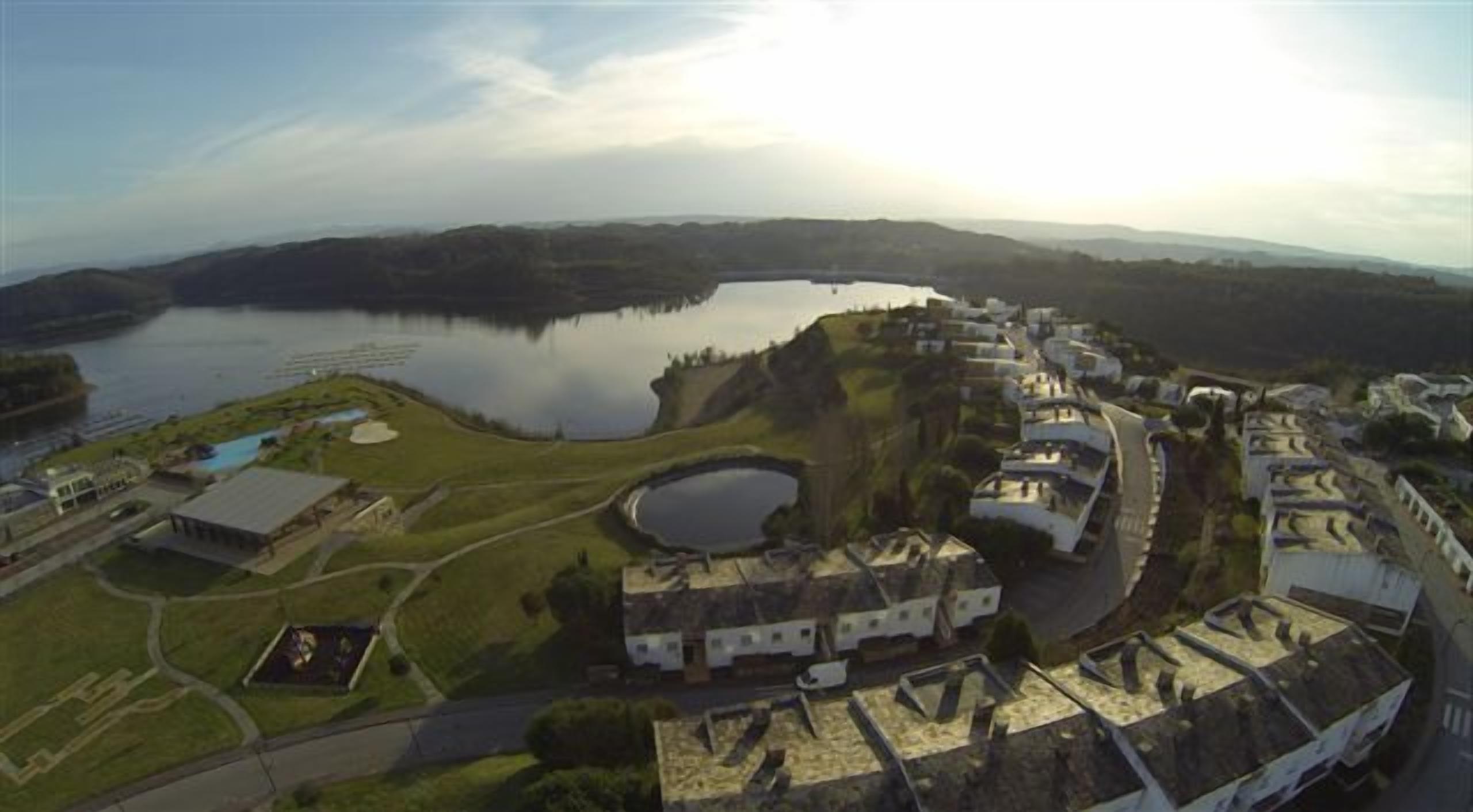 Vista aérea de um resort costeiro com um lago grande, uma marina e uma série de edifícios com estilo arquitetônico uniforme.
