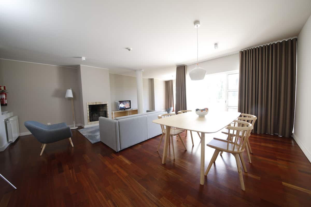 Ein modernes Wohnzimmer mit Esstisch, Stühlen, einer Couch und einem Fernseher.