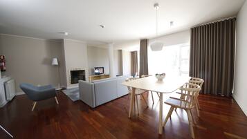 A modern living room with a dining table, chairs, a sofa, and a television.