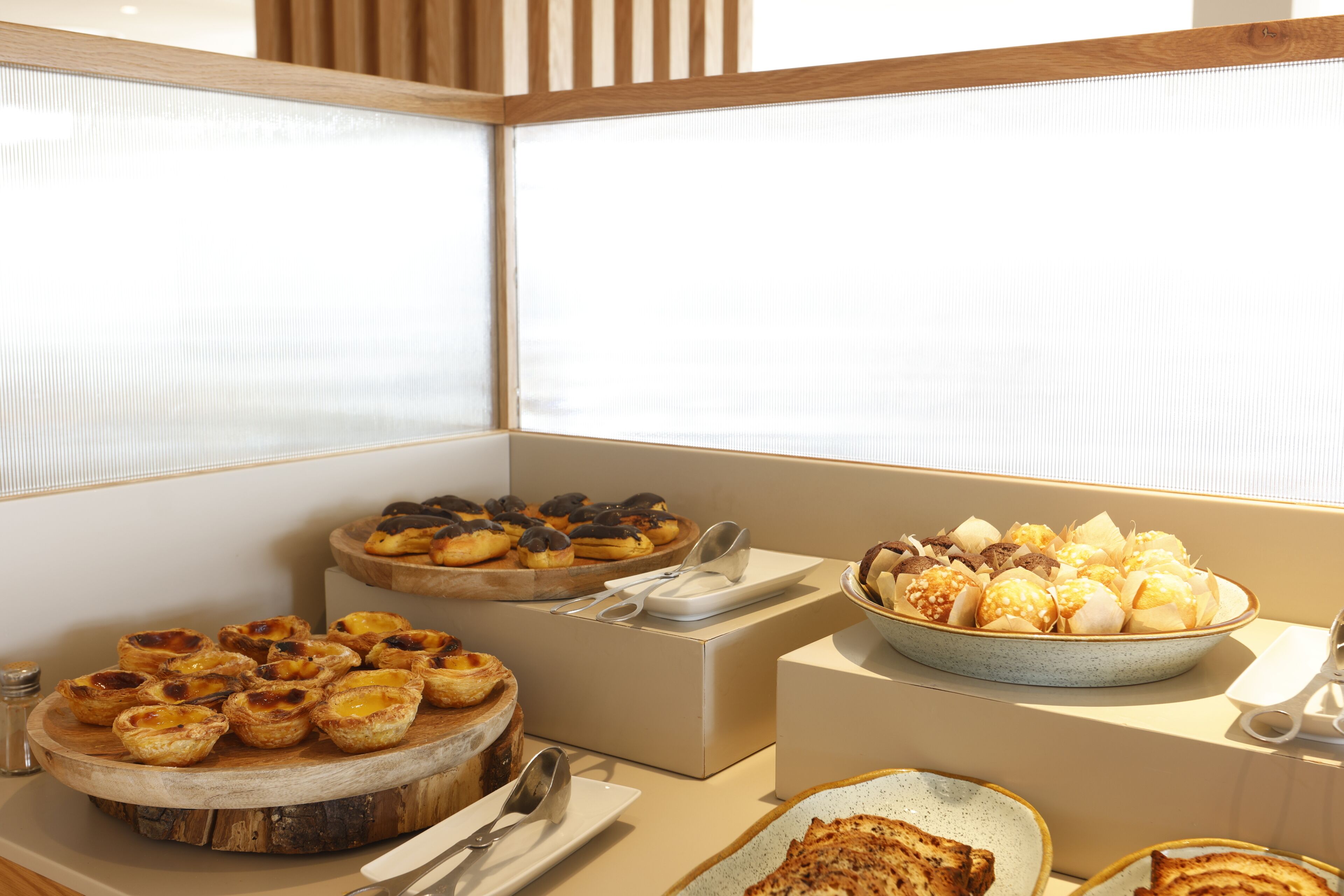 A buffet with various food items, including pastries and bread, arranged on wooden and ceramic serving dishes.