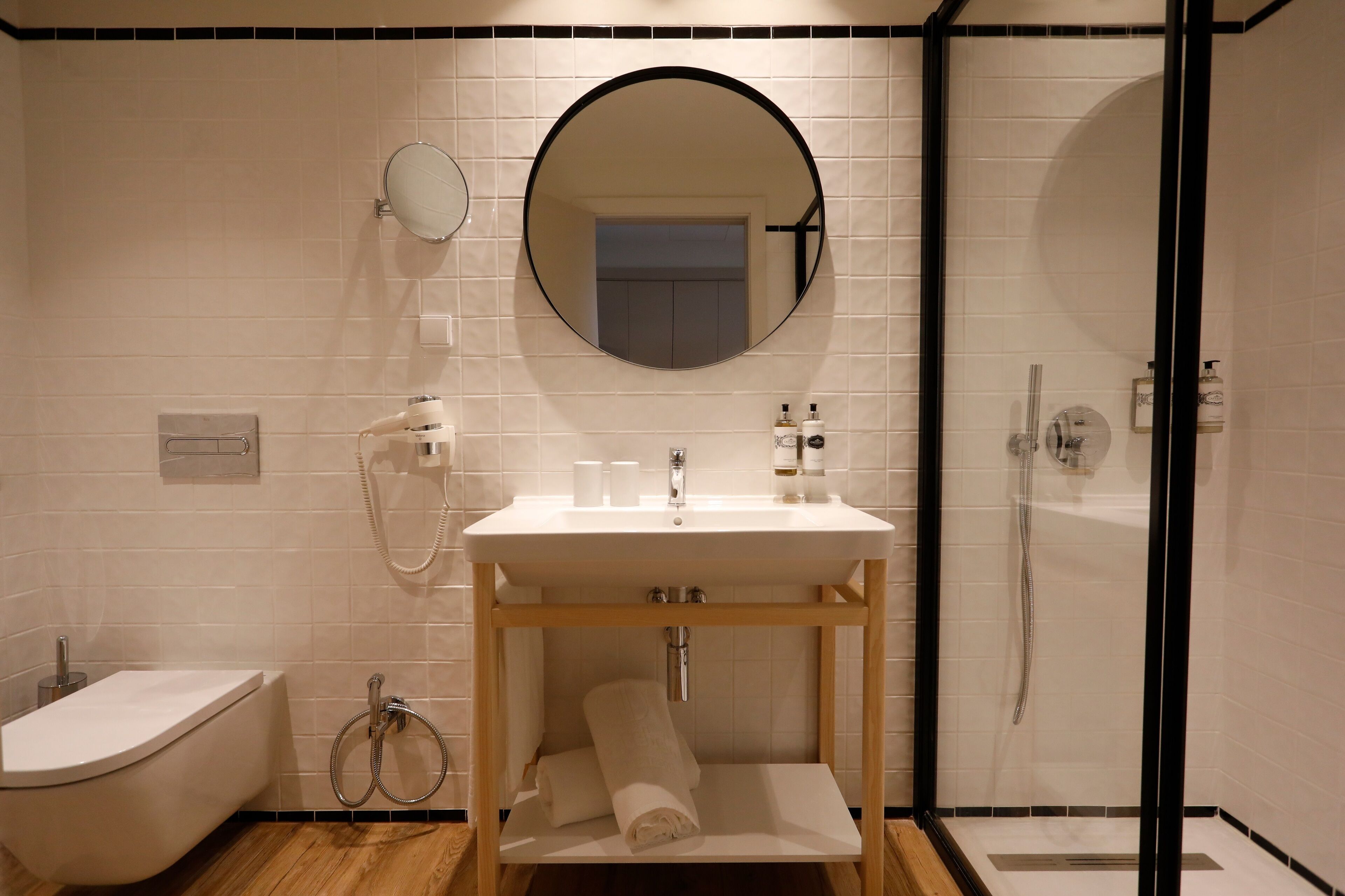 Une salle de bain moderne avec un lavabo, un miroir et des toilettes, le tout de couleur blanche.