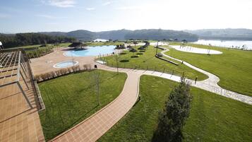 A resort with a swimming pool, walking paths, and a view of a lake and mountains.