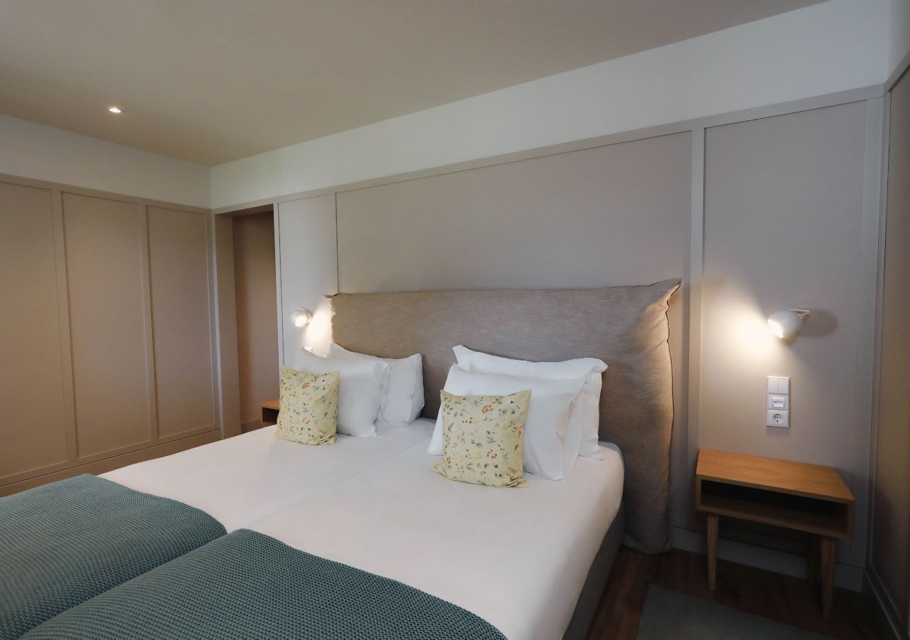 Une chambre d’hôtel avec un grand lit, des tables de chevet et un luminaire fixé au mur.