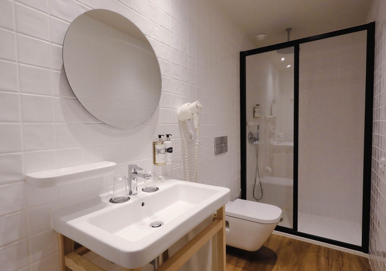 Ein Badezimmer mit Waschbecken, Spiegel und Toilette sowie einer Duschkabine.