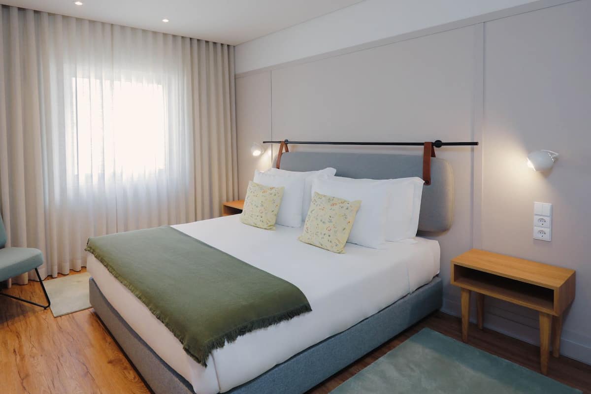 Ein modernes Hotelzimmer mit einem großen Bett, einer Sitzecke und einem Fernseher.