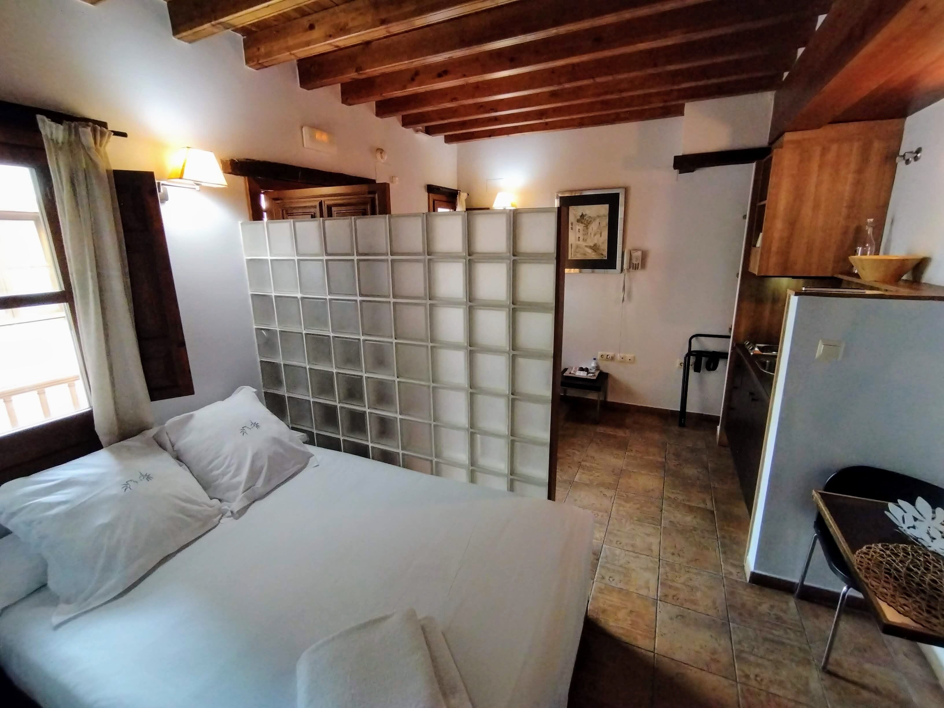 Une chambre à coucher comprenant un lit, une armoire, un bureau, une chaise, un réfrigérateur et une fenêtre avec des rideaux.