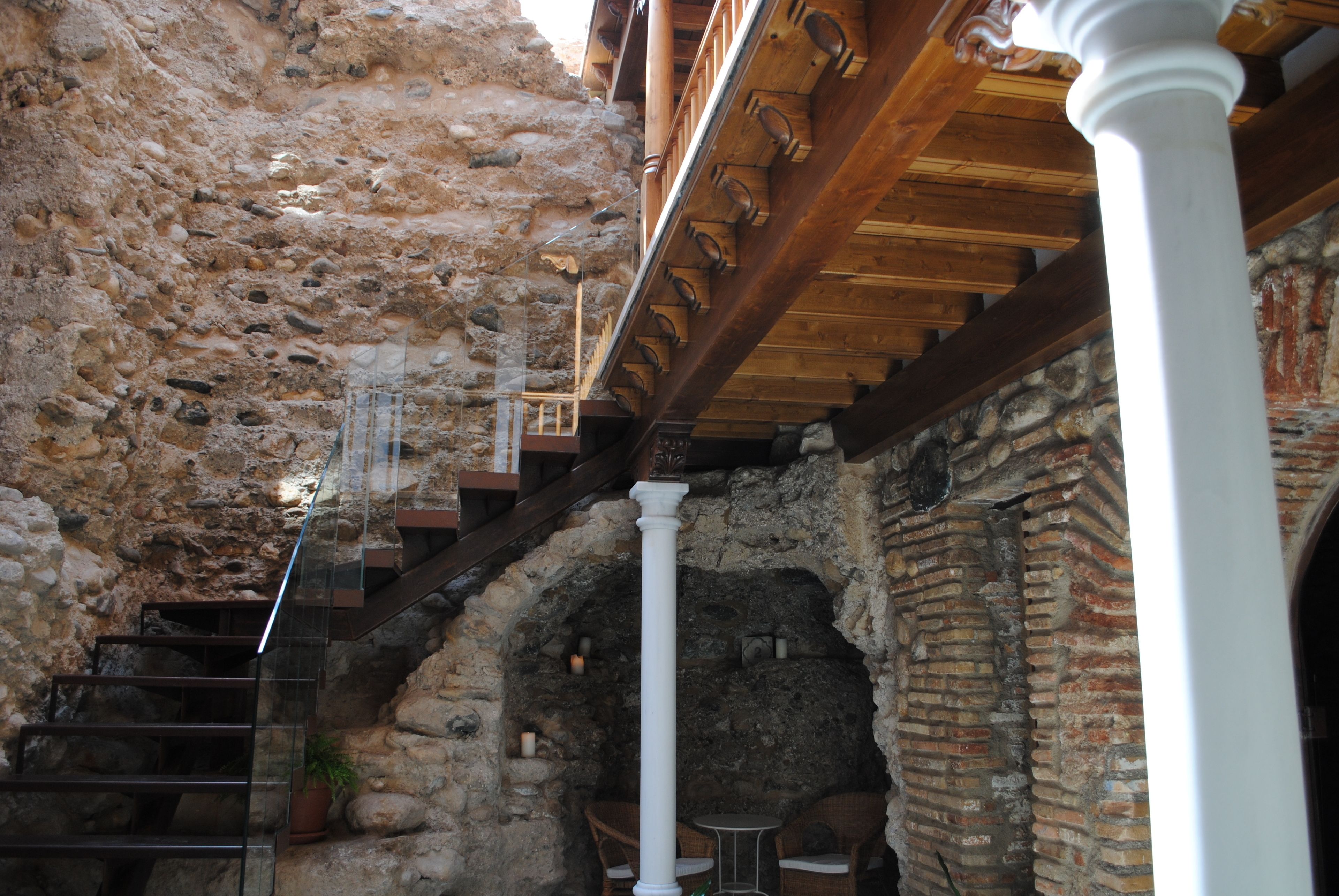 Un intérieur en pierre agrémenté d’un escalier en bois, de colonnes blanches et de murs en briques.