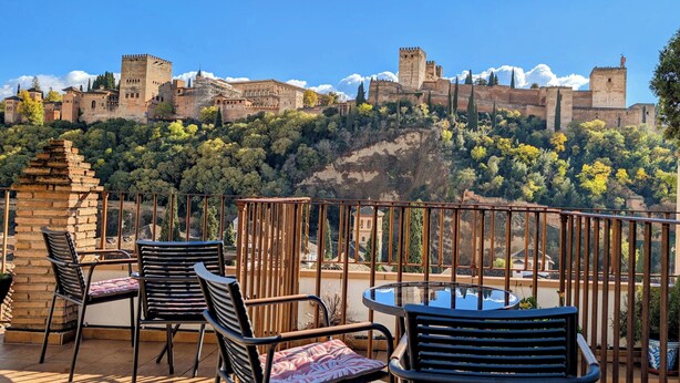 A terrace with outdoor seating and a view of a historic castle. - Apartamentos Turísticos Alhambra (Granada)
