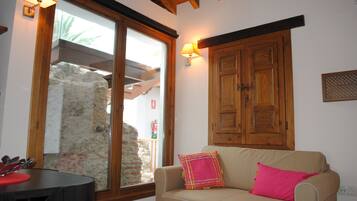 Una sala de estar con un sofá beige, un aparador de madera y un ventanal con vistas a una pared de piedra.