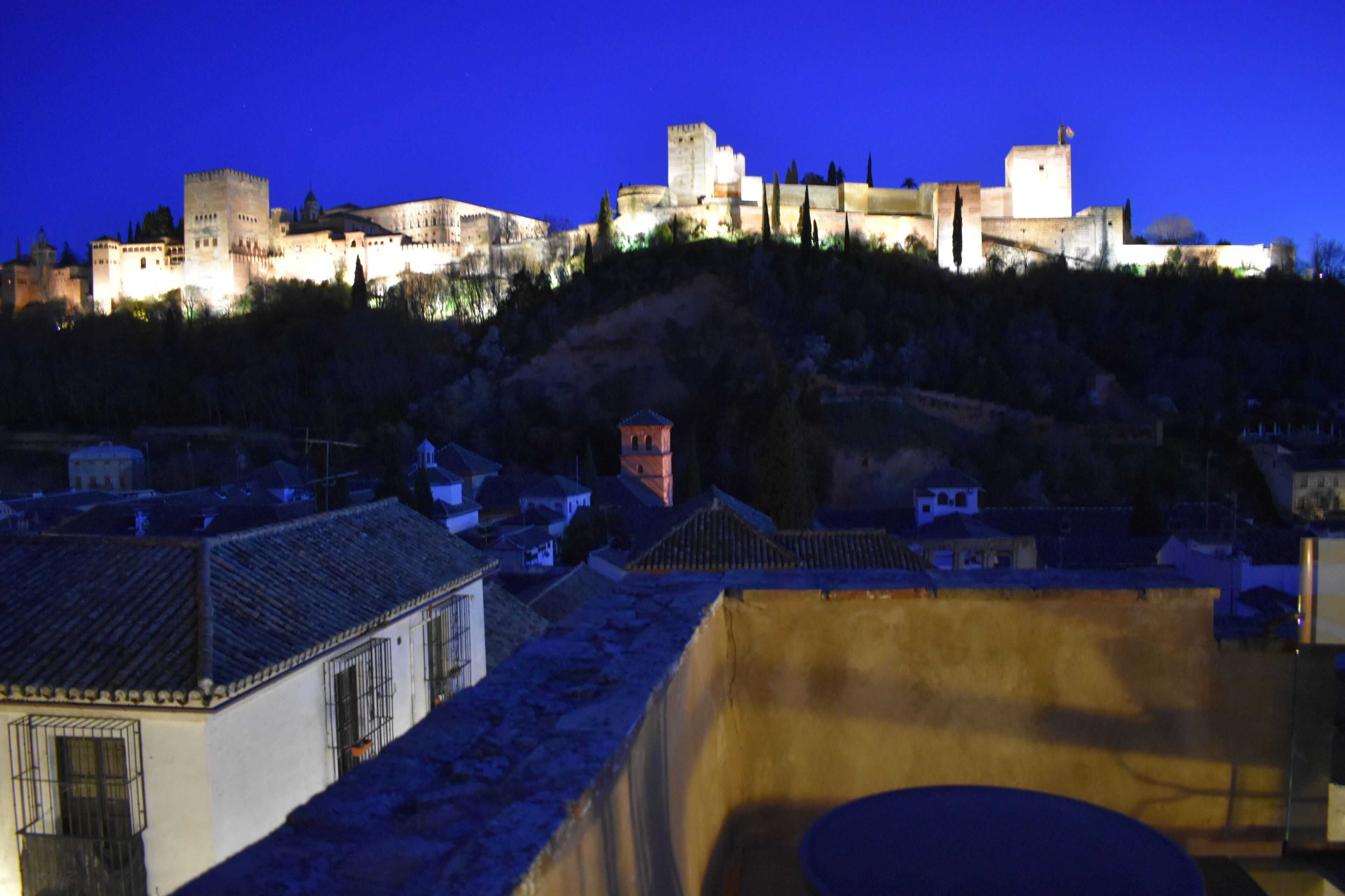 A historic castle with multiple towers and walls, situated on a hill overlooking a town with traditional buildings.