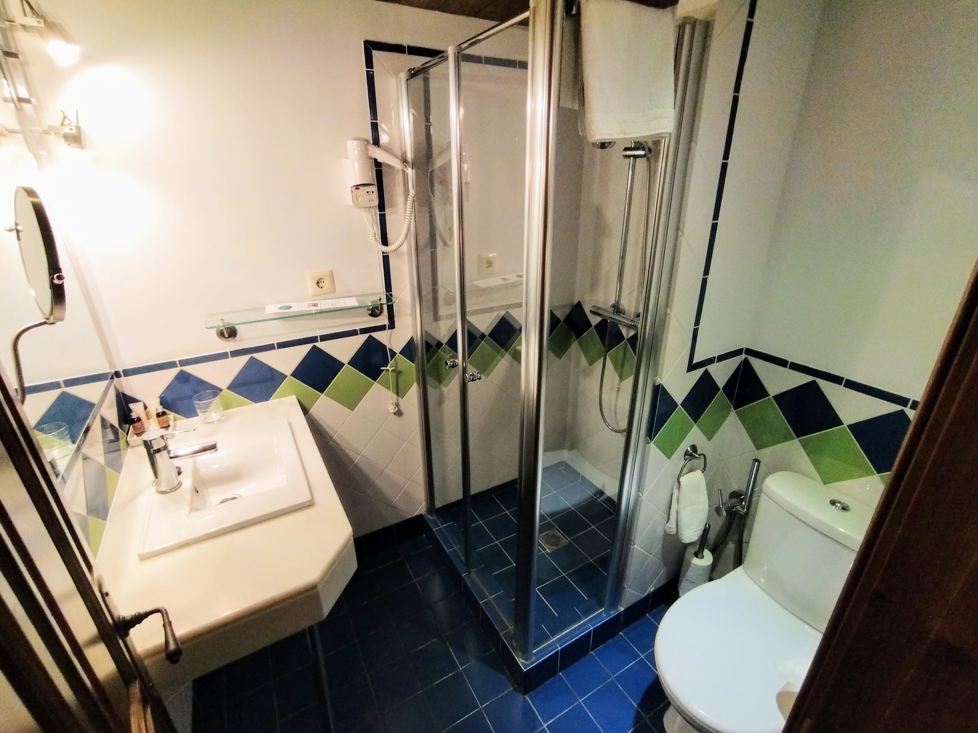 Un baño con ducha acristalada, lavamanos blanco y retrete.
