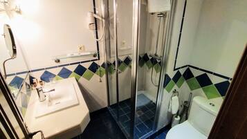 Un baño con ducha acristalada, lavamanos blanco y retrete.