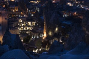 A nighttime view of a city with prominent rock formations and illuminated buildings. - Anatolian Houses Cave Hotel & SPA (Nevsehir)