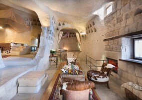 Un intérieur rustique avec des murs en pierre, une cheminée et un coin salon avec une table dressée pour le repas.