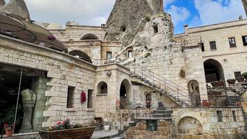 Un patio con piscina, edificios de piedra y una gran formación rocosa.