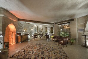 A spacious lobby with a large patterned rug, stone walls, and a leather sofa.