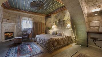 Un dormitorio con chimenea de piedra, una cama grande y techo de madera.