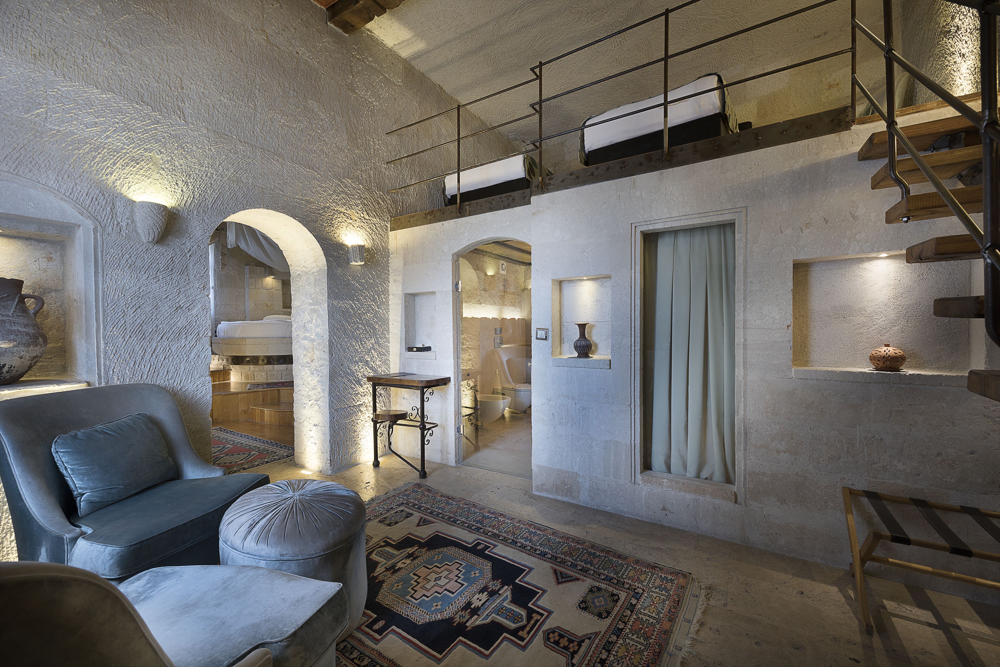 A spacious living area with a high ceiling, a staircase, and a view into the kitchen.