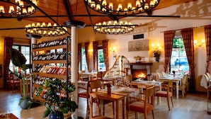 A restaurant with multiple dining tables, chairs, and a wine rack with bottles. - Wineport Lodge Agva (Sile)