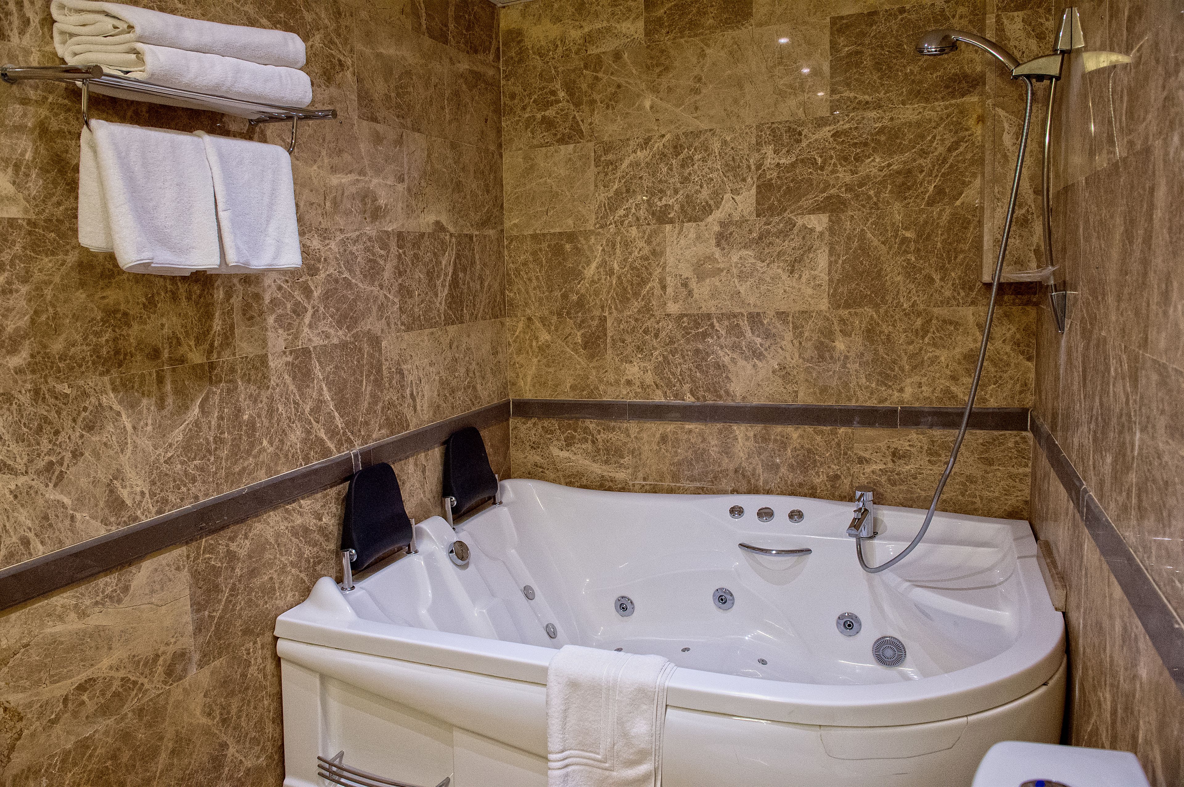 Un baño con pared de mármol, una bañera y una ducha.