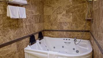 Un baño con pared de mármol, una bañera y una ducha.