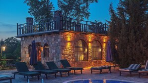 A stone building with a balcony, a pool, and lounge chairs. - Wineport Lodge Agva (Sile)